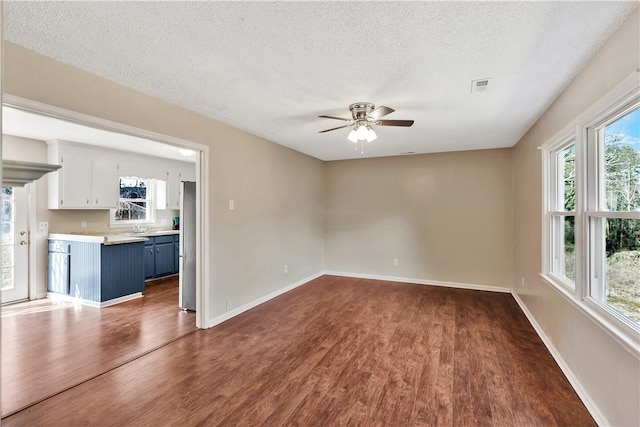 empty room with dark wood-type flooring, ceiling fan, sink, and a textured ceiling