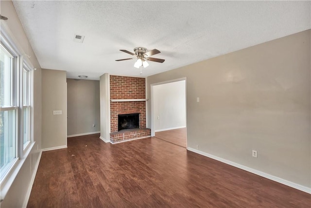 unfurnished living room featuring ceiling fan, a fireplace, dark hardwood / wood-style floors, and a textured ceiling