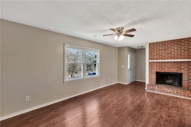 unfurnished living room featuring dark hardwood / wood-style flooring, a brick fireplace, a textured ceiling, and ceiling fan