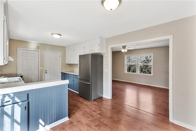 kitchen with dark wood-type flooring, sink, stainless steel refrigerator, ceiling fan, and white cabinets