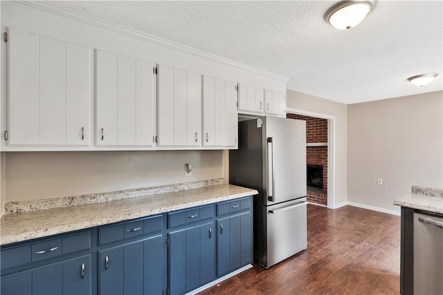 kitchen featuring stainless steel appliances, blue cabinets, a textured ceiling, white cabinets, and dark hardwood / wood-style flooring