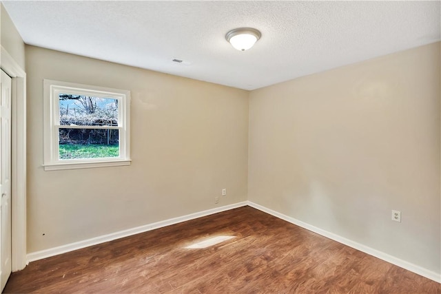 spare room featuring hardwood / wood-style flooring and a textured ceiling