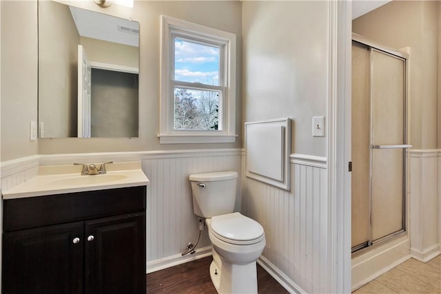 bathroom featuring vanity, toilet, and a shower with shower door