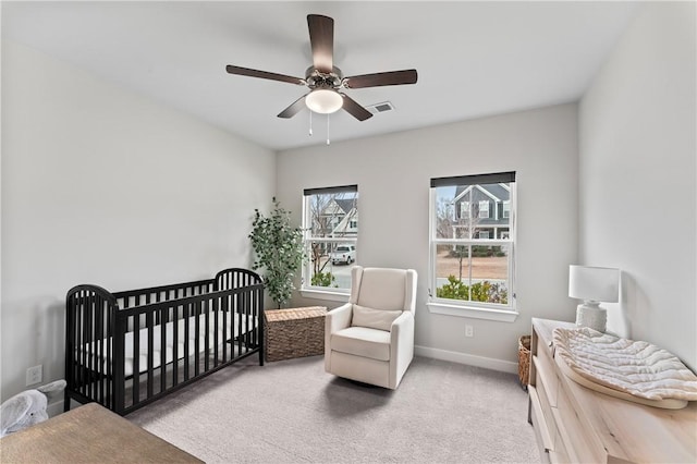 bedroom with a nursery area, ceiling fan, and carpet flooring