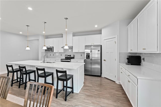 kitchen with a kitchen island with sink, hanging light fixtures, sink, and appliances with stainless steel finishes