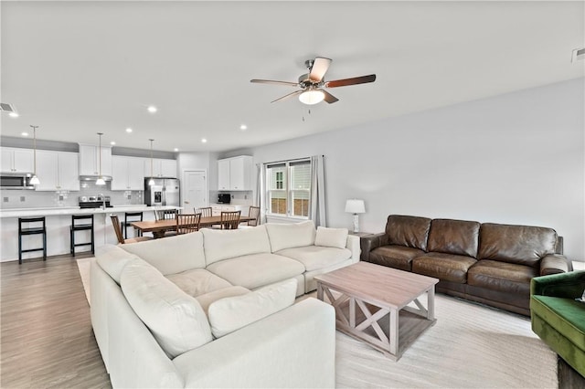 living room with ceiling fan and light wood-type flooring