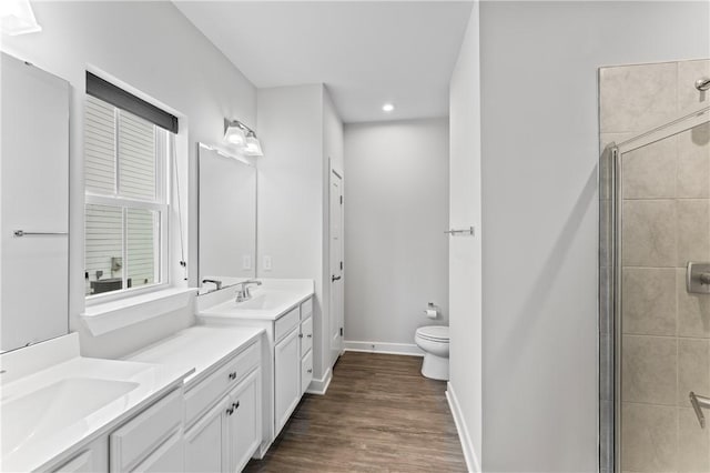 bathroom featuring toilet, vanity, a shower with door, hardwood / wood-style flooring, and a healthy amount of sunlight