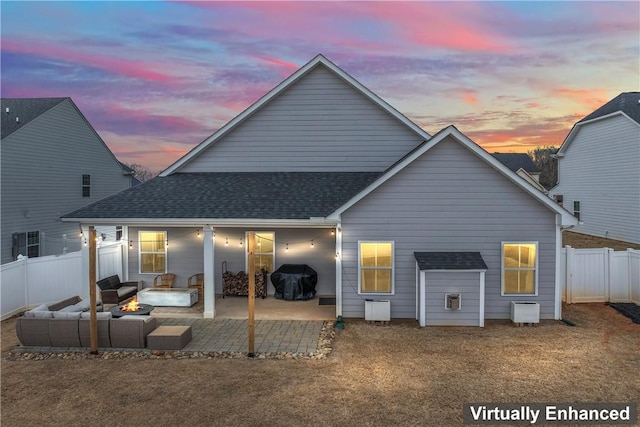 back house at dusk featuring an outdoor living space and a patio