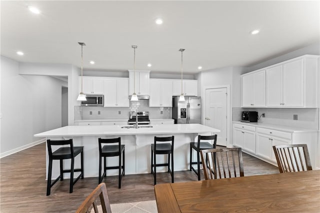 kitchen featuring pendant lighting, sink, white cabinets, a kitchen island with sink, and stainless steel appliances