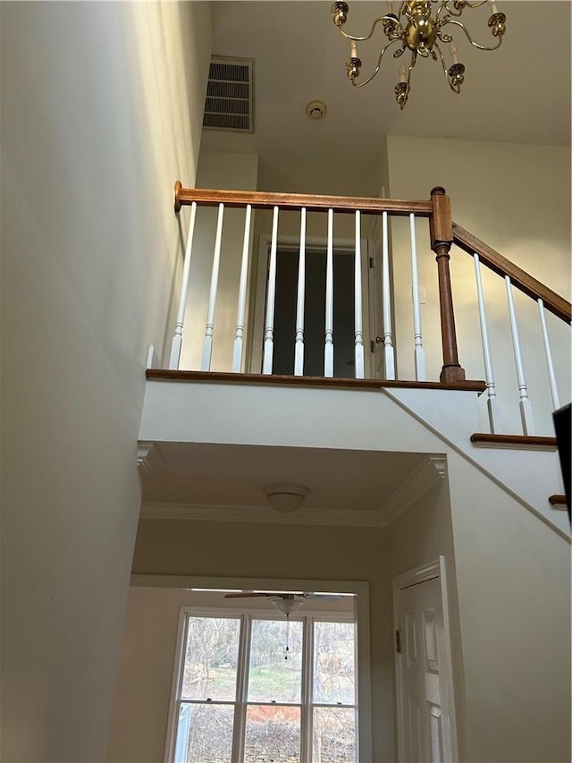 stairway featuring ornamental molding and a chandelier