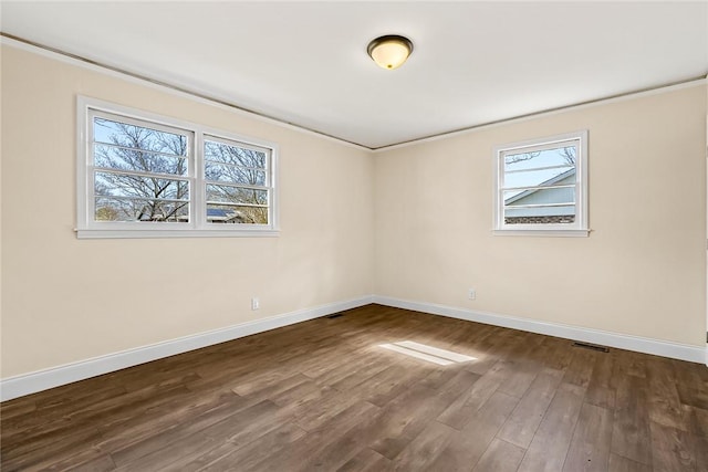 unfurnished room with dark wood-type flooring, visible vents, crown molding, and baseboards