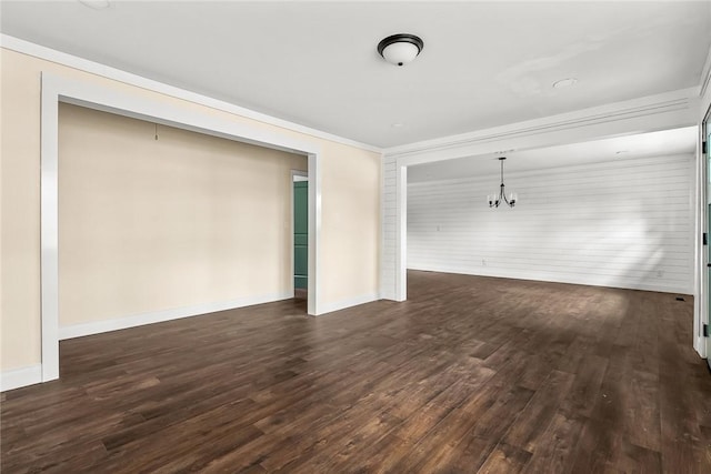 unfurnished room featuring dark wood-type flooring, baseboards, and an inviting chandelier