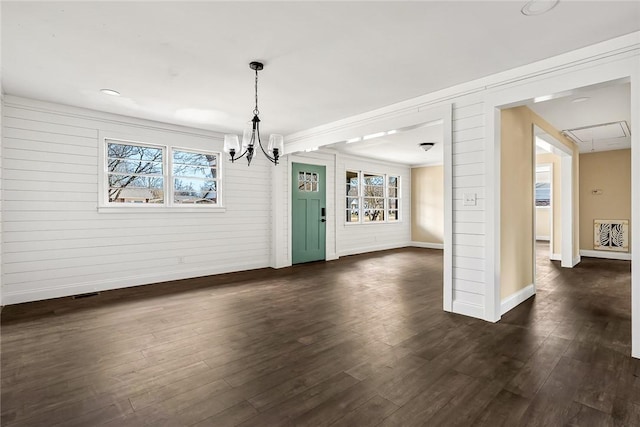 unfurnished dining area with dark wood-style flooring, visible vents, attic access, ornamental molding, and baseboards