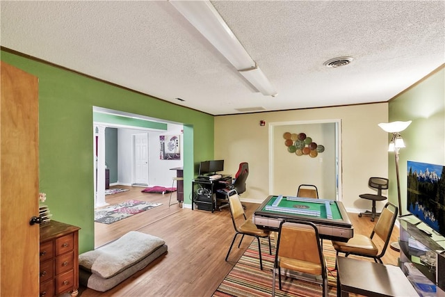 dining area with hardwood / wood-style floors, crown molding, and a textured ceiling