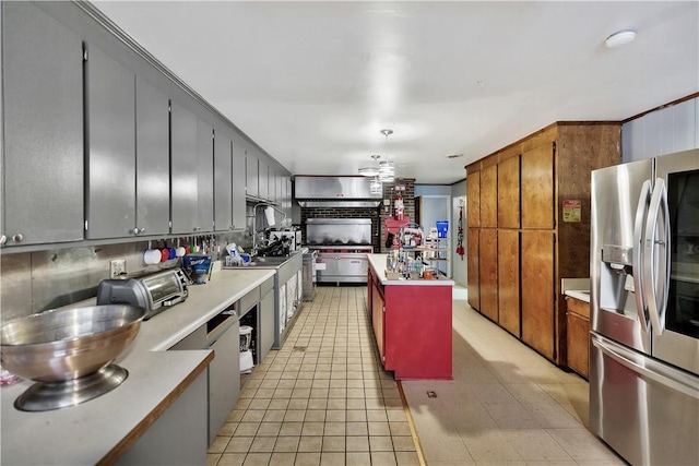 kitchen featuring light tile patterned floors, ceiling fan, hanging light fixtures, a center island, and stainless steel refrigerator with ice dispenser