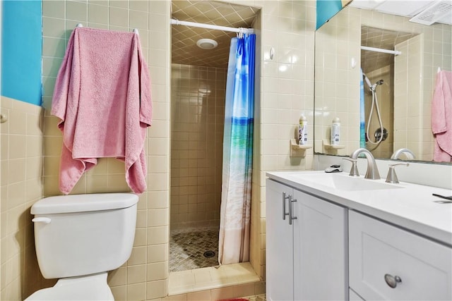 bathroom featuring tile walls, vanity, toilet, and walk in shower