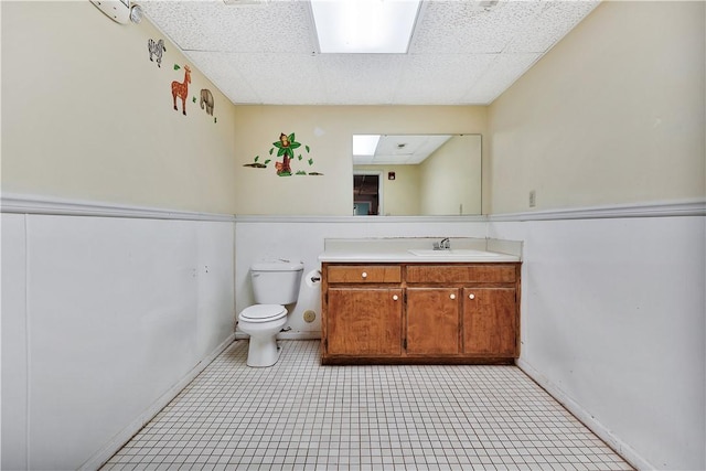 bathroom with a skylight, vanity, a paneled ceiling, and toilet