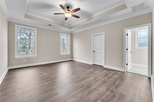 unfurnished bedroom with a tray ceiling, ornamental molding, dark hardwood / wood-style floors, and ceiling fan