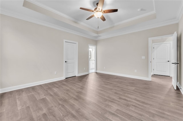 spare room with ceiling fan, ornamental molding, a raised ceiling, and light hardwood / wood-style flooring