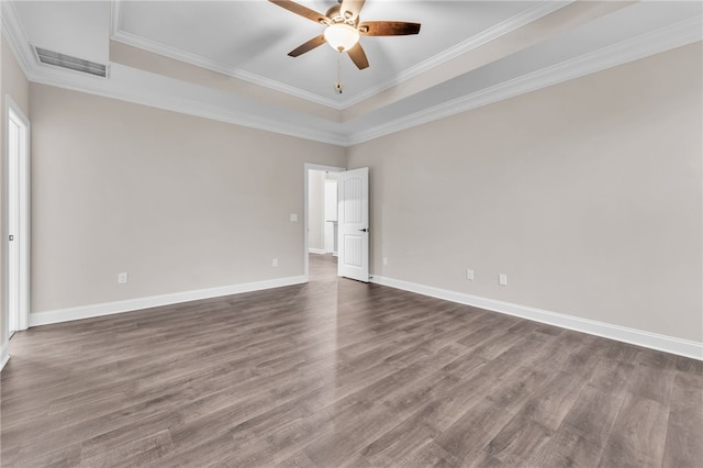 unfurnished room featuring ornamental molding, dark wood-type flooring, ceiling fan, and a tray ceiling