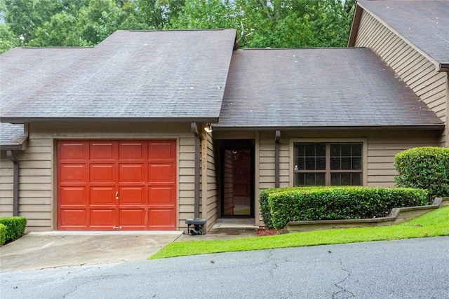 view of front of property featuring a garage, driveway, and a shingled roof