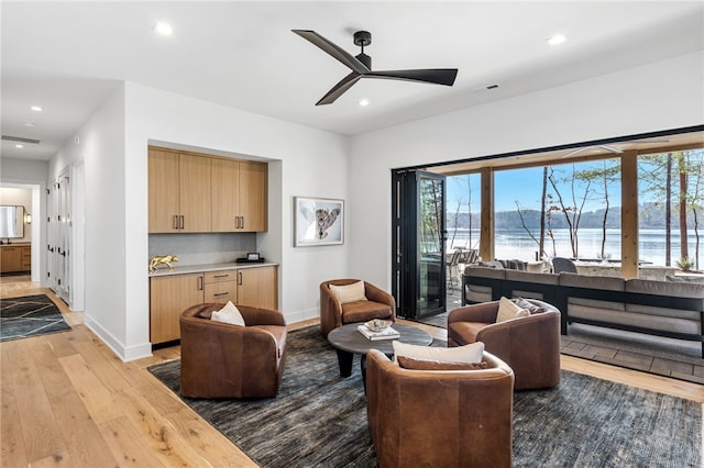 living room with a water view, ceiling fan, and light hardwood / wood-style flooring