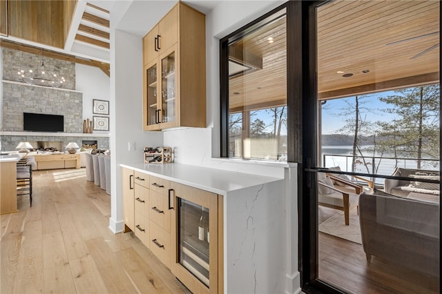 kitchen with light brown cabinets, pendant lighting, beverage cooler, and light wood-type flooring