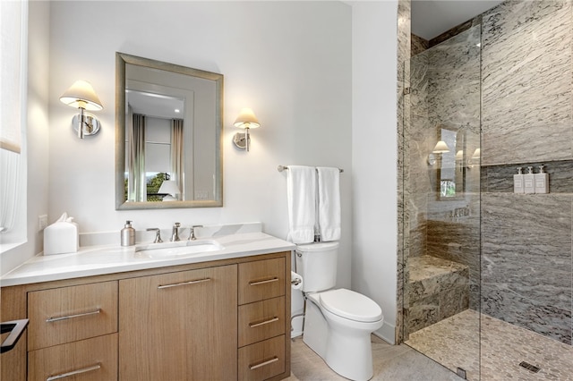 bathroom with tiled shower, vanity, and toilet