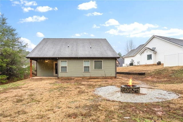 rear view of house with a yard and an outdoor fire pit