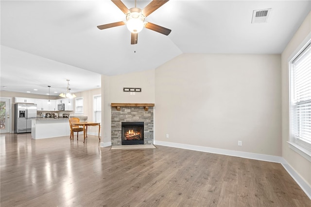 unfurnished living room with wood-type flooring, vaulted ceiling, and a healthy amount of sunlight