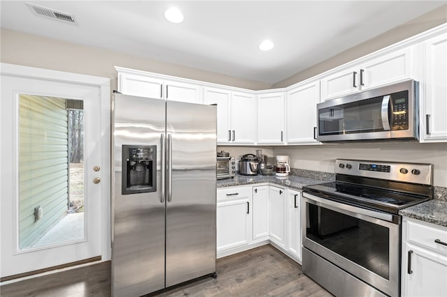 kitchen featuring stainless steel appliances, white cabinetry, dark wood-type flooring, and dark stone counters