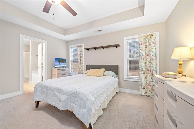 bedroom featuring multiple windows, a tray ceiling, and light carpet