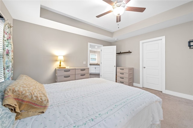 carpeted bedroom with a raised ceiling and ceiling fan