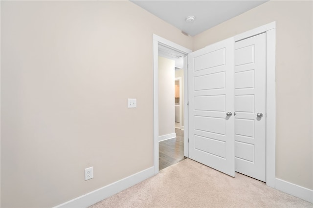 unfurnished bedroom featuring light colored carpet and a closet