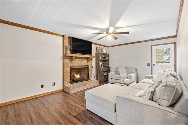 living room featuring ceiling fan, dark wood-type flooring, crown molding, and a fireplace