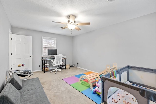 recreation room featuring ceiling fan, light colored carpet, and a textured ceiling