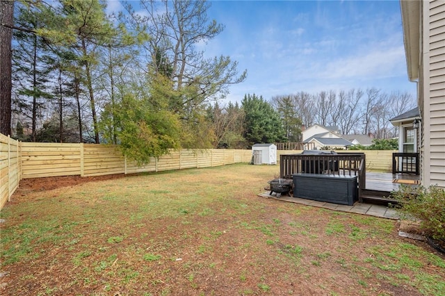 view of yard featuring a storage unit, a deck, and a jacuzzi