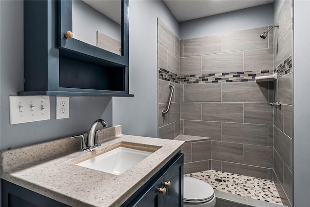 bathroom featuring vanity, tiled shower, and toilet