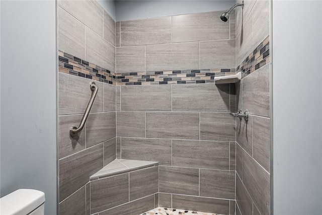 bathroom featuring a tile shower and toilet