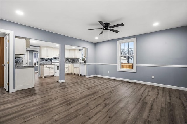 unfurnished living room featuring dark wood-type flooring and ceiling fan