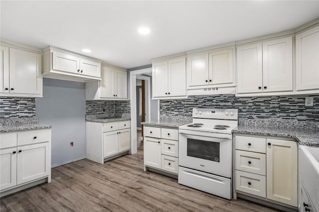 kitchen featuring hardwood / wood-style floors, white cabinets, decorative backsplash, electric range, and light stone counters