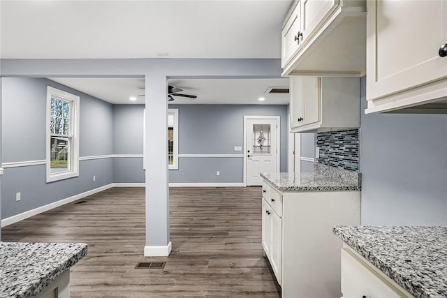 kitchen featuring decorative backsplash, dark wood-type flooring, light stone countertops, and ceiling fan