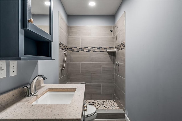 bathroom featuring vanity, toilet, and tiled shower