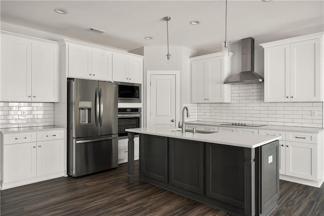 kitchen with wall chimney range hood, sink, hanging light fixtures, stainless steel appliances, and white cabinets