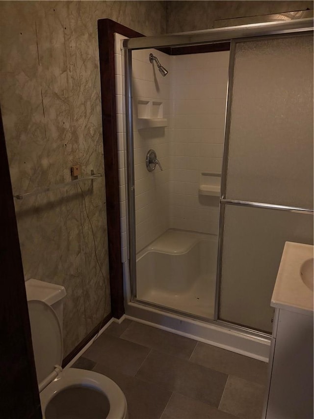 bathroom with an enclosed shower, vanity, tile patterned flooring, and toilet