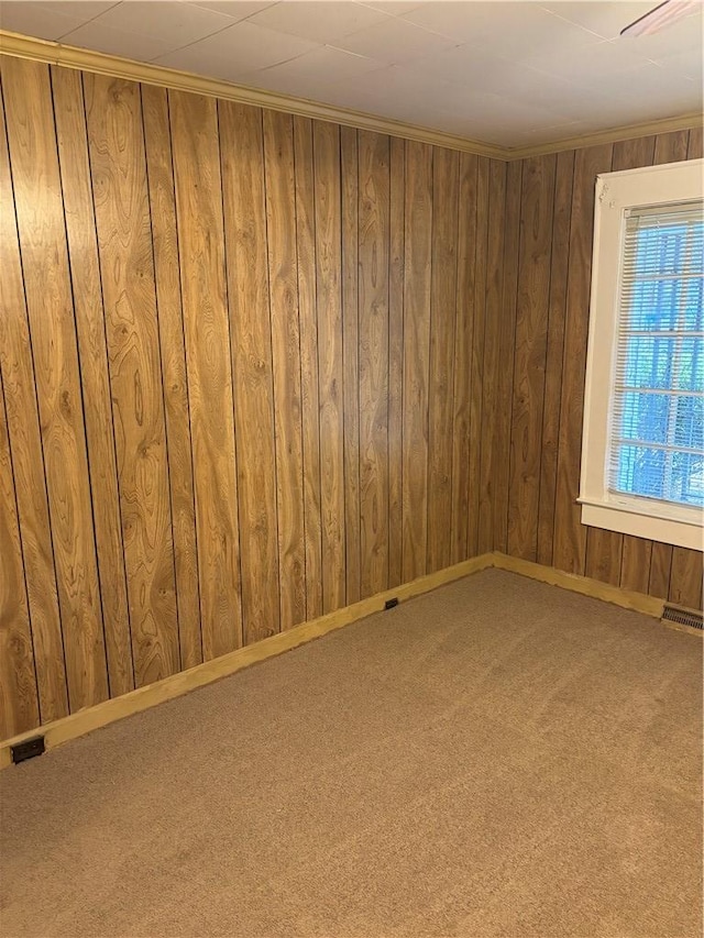 carpeted empty room with crown molding and wood walls