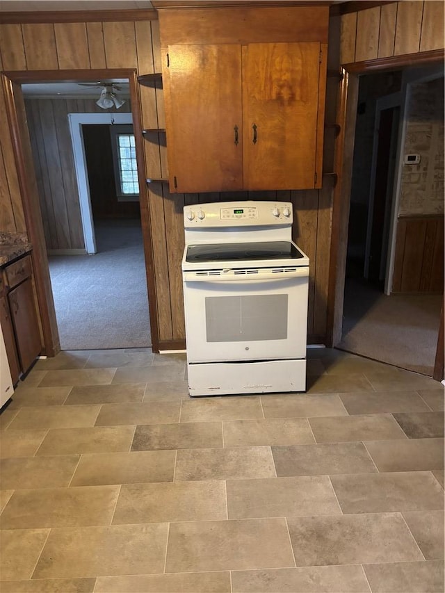 kitchen featuring light carpet, white electric range, wooden walls, and ceiling fan