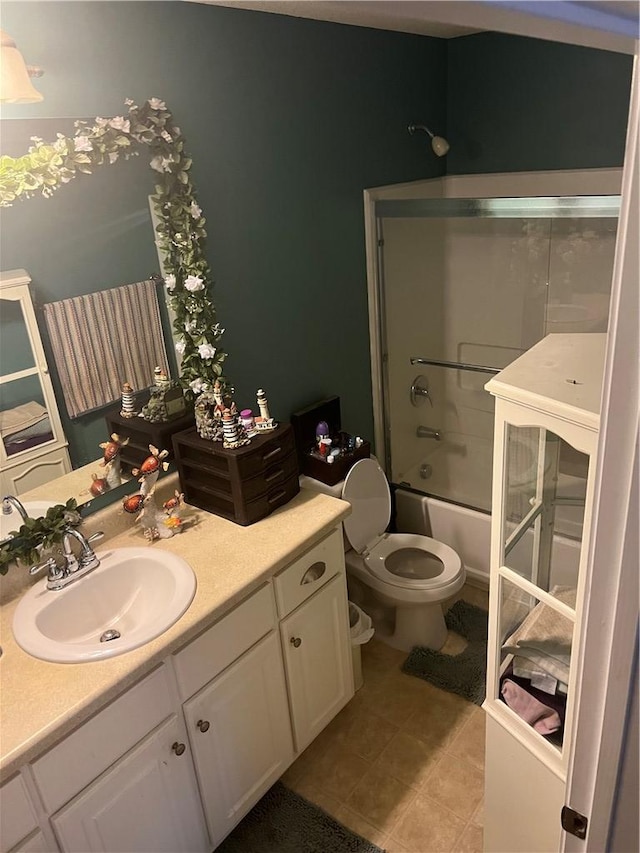 full bathroom with toilet, vanity, bath / shower combo with glass door, and tile patterned flooring