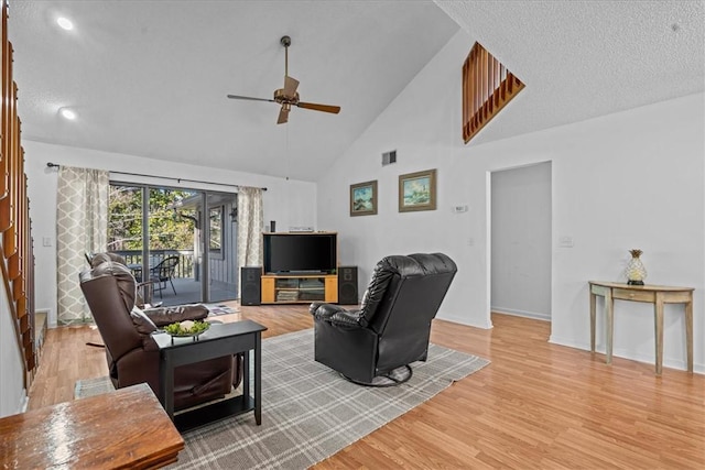 living room with a textured ceiling, high vaulted ceiling, ceiling fan, and light wood-type flooring