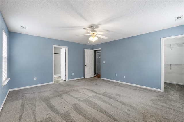 unfurnished bedroom with a spacious closet, carpet floors, a textured ceiling, and ceiling fan